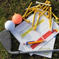 Golf scorecards, tees and putter on grass
